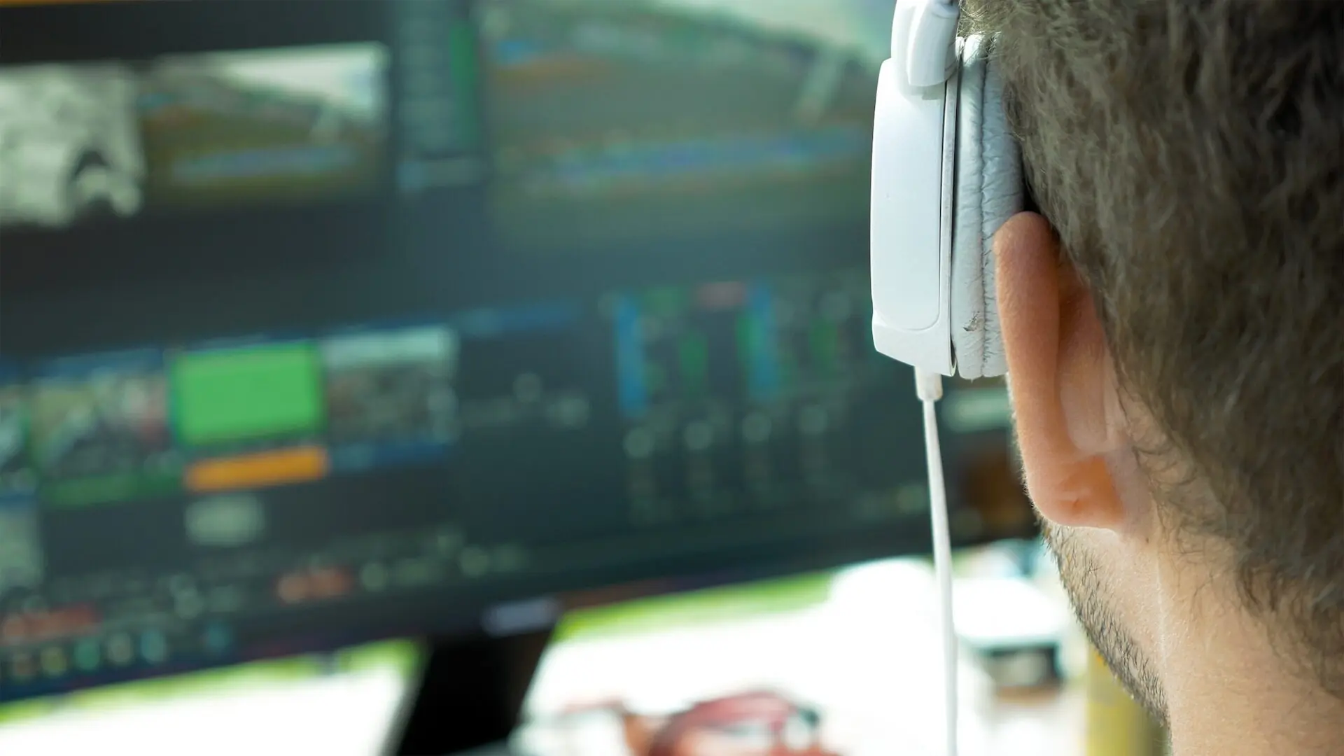 Video broadcast editor with headphones at screen